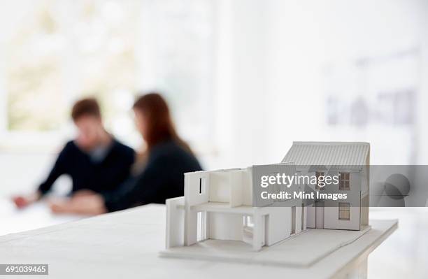 architects model of a building with two people at a meeting out of focus in the background. communication. - architekturmodell stock-fotos und bilder