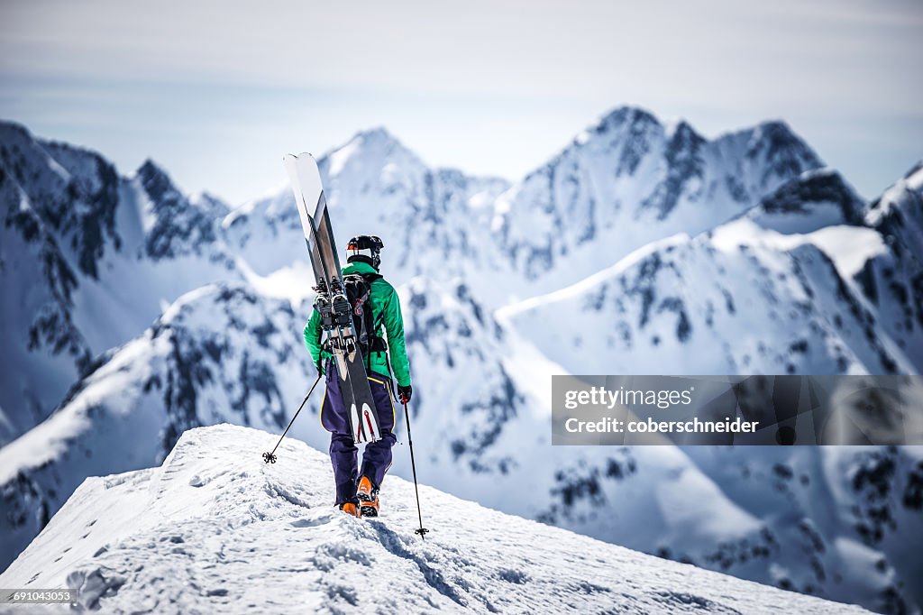Skier walking along ridge carrying his skis, Andermatt, Uri, Switzerland
