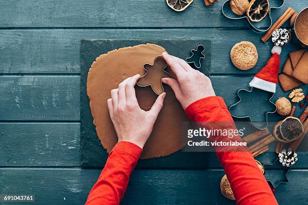 girl making gingerbread men cookies - pastry cutter stockfoto's en -beelden