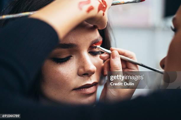 make up artist applying eye shadow to a woman - maquilhador imagens e fotografias de stock