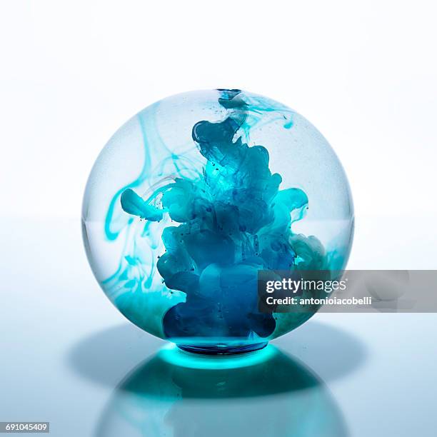 crystal ball filled with blue watercolor paint in water - crystal ball stock pictures, royalty-free photos & images