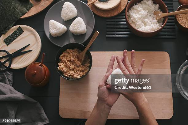 woman's hands preparing onigiris - bola de arroz fotografías e imágenes de stock