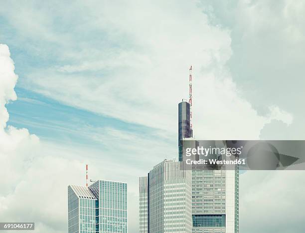 germany, frankfurt, upper parts of two skyscrapers in front of dramatic clouds - minder verzadiging stockfoto's en -beelden