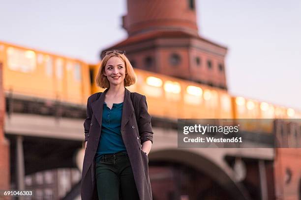germany, berlin, portrait of smiling young woman in front of oberbaum bridge in the evening - berlin people ストックフォトと画像