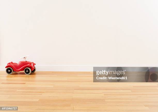 red pedal car standing on parquet - macchina a pedali foto e immagini stock