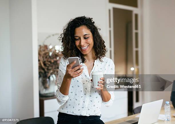 businesswoman in office using smart phone, holding cup of coffee - texting europe stock pictures, royalty-free photos & images