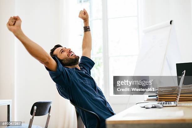 businessman stretching at desk - braccia alzate foto e immagini stock
