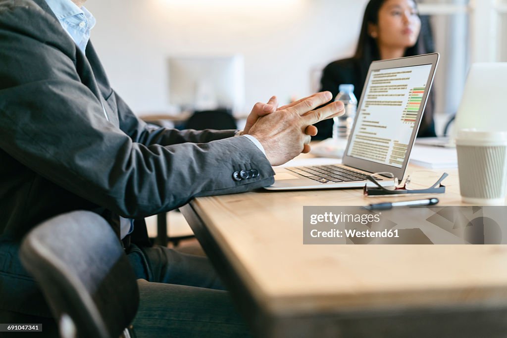 Businessman sitting in meeting, using laptop