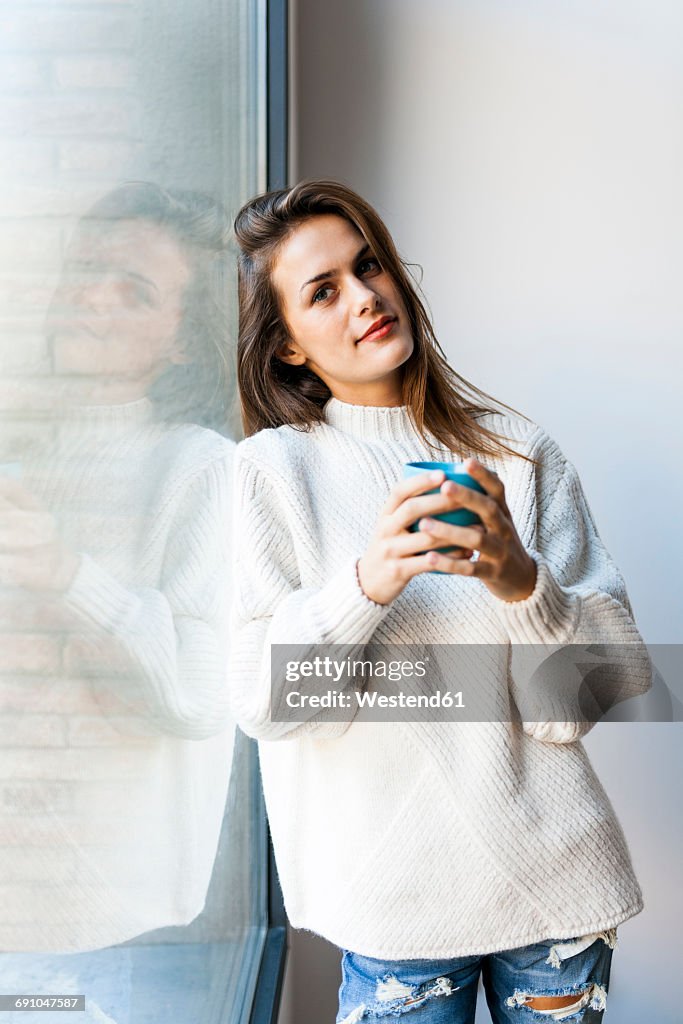 Young woman drinking a coffee at a window