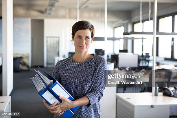 businesswoman in office holding folders - administration photos et images de collection