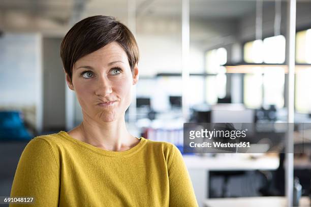 businesswoman in office thinking - female puckered lips stockfoto's en -beelden