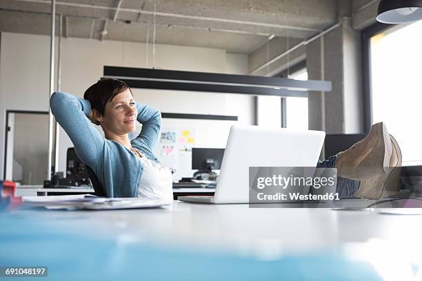 businesswoman in office at desk relaxing - hands behind head stock pictures, royalty-free photos & images