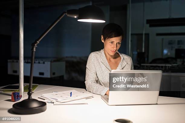 businesswoman in office using laptop in the dark - working late stock-fotos und bilder