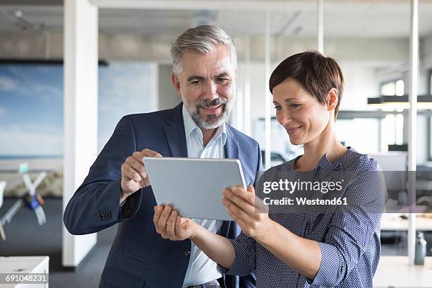 businessman and businesswoman with tablet in office - 2 frauen gespräch stock-fotos und bilder