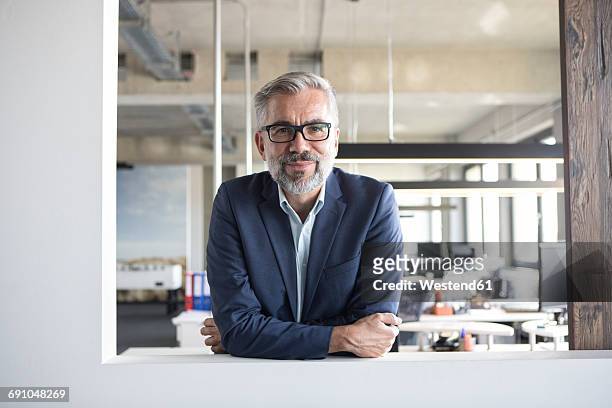 portrait of confident businessman in office - männer über 40 stock-fotos und bilder