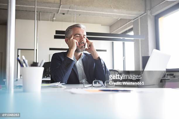 businessman at desk in office with closed eyes - grey hair stress stock pictures, royalty-free photos & images