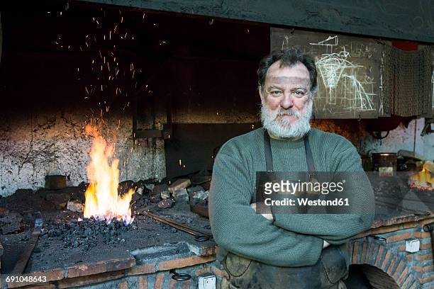 portrait of confident blacksmith in his workshop - blacksmith sparks stock-fotos und bilder