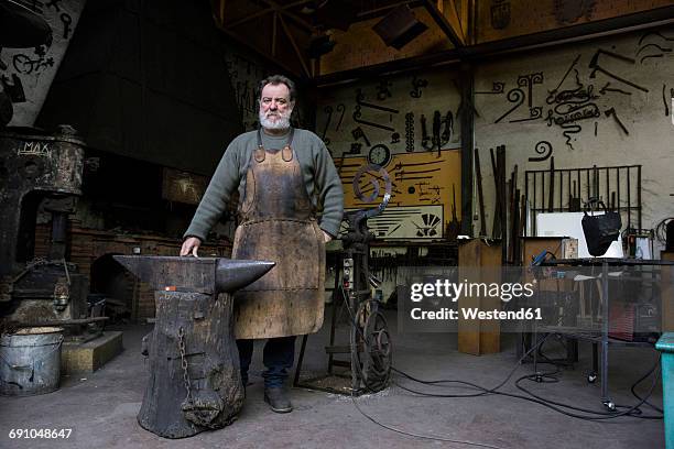 portrait of confident blacksmith in his workshop - industrial portraits character photos et images de collection
