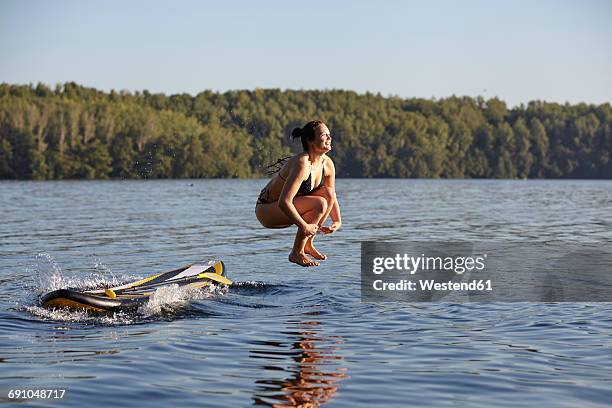 woman jumping into water from paddleboard - human cannon stock pictures, royalty-free photos & images