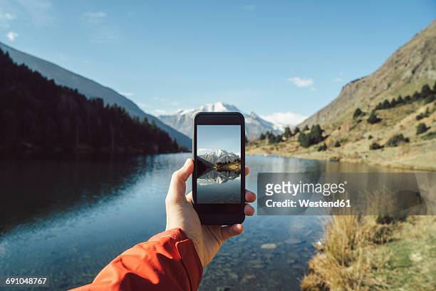 france, pyrenees, pic carlit, man taking a picture at mountain lake - photophone fotografías e imágenes de stock