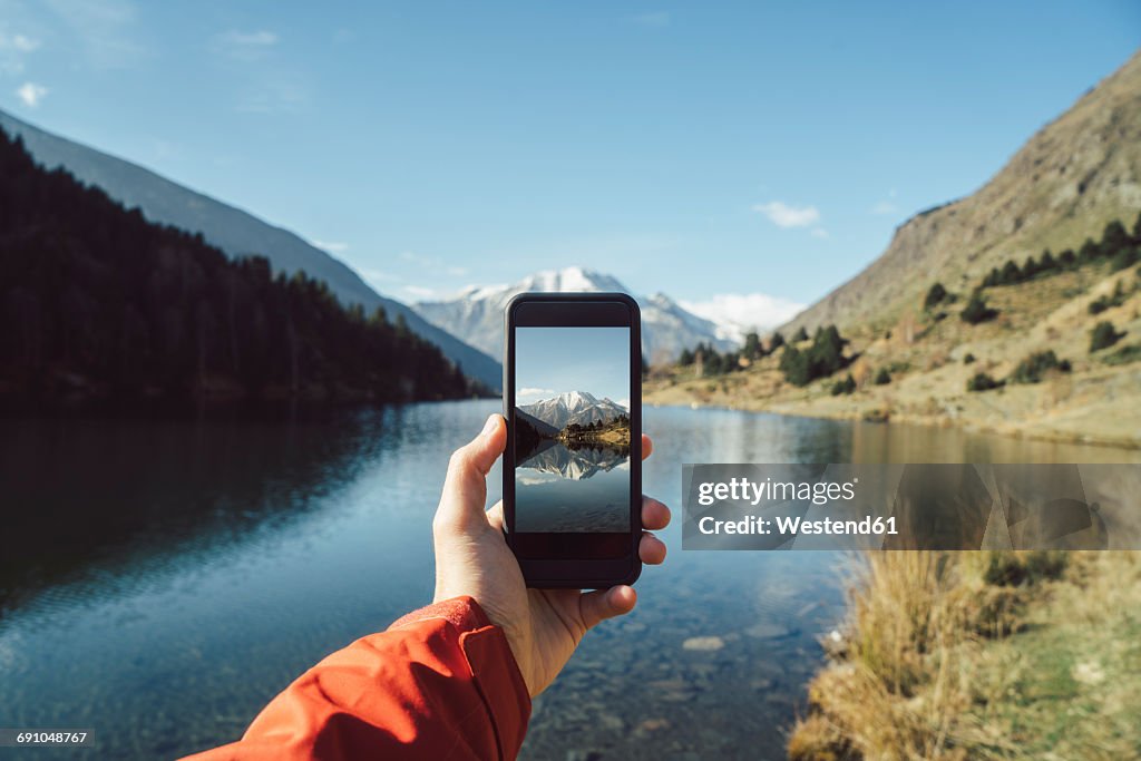 France, Pyrenees, Pic Carlit, man taking a picture at mountain lake