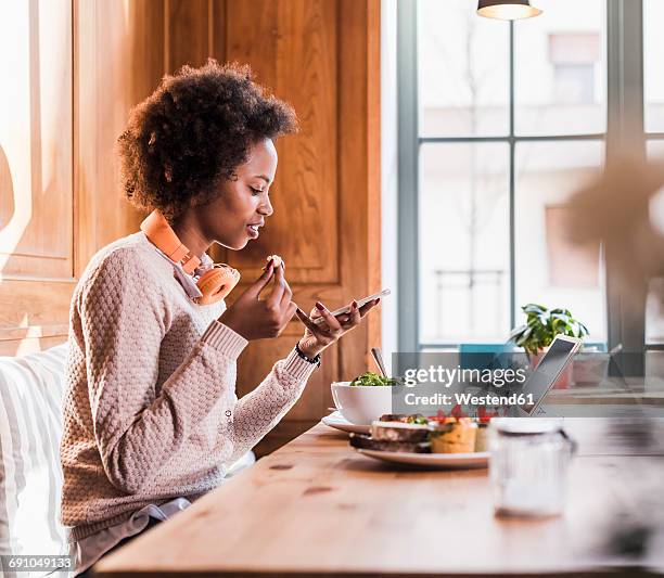 young woman using cell phone in a cafe - telecommuting eating stock pictures, royalty-free photos & images