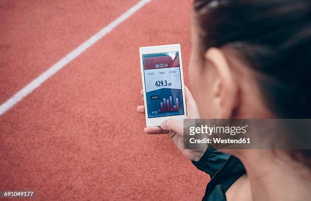 athlete looking on smartphone with training data on display - track and field stadium stockfoto's en -beelden