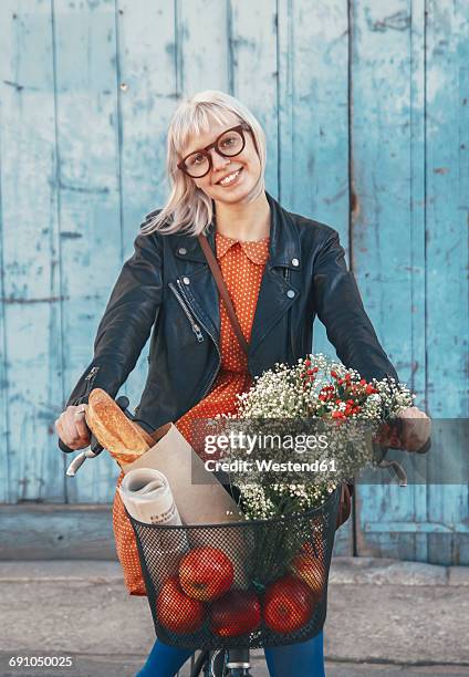 smiling young woman with groceries on bicycle - white flower paper stock-fotos und bilder