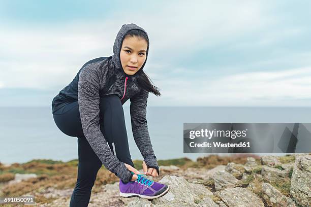 ireland, howth, woman lacing her shoes at cliff coast - tiersport stock pictures, royalty-free photos & images