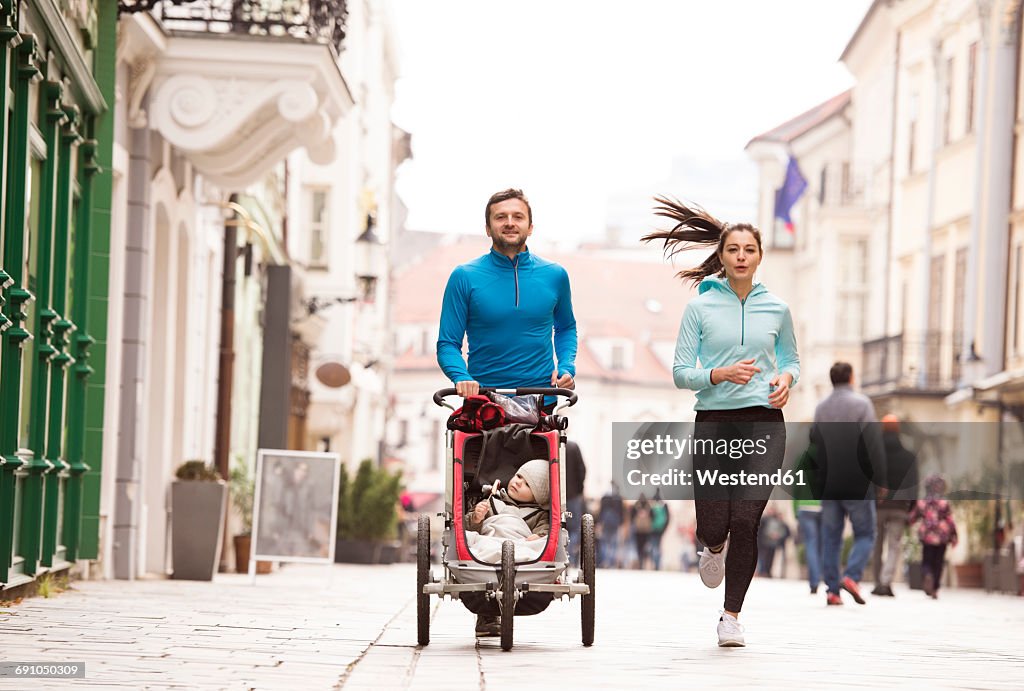 Parents running with child in stroller in the city