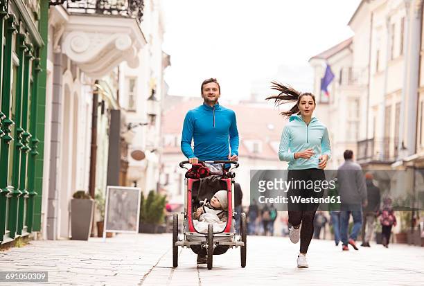 parents running with child in stroller in the city - family jogging stock pictures, royalty-free photos & images