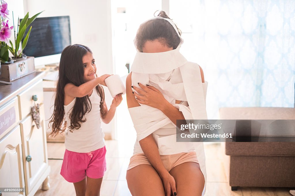 Playful teenage girl and her little sister on couch