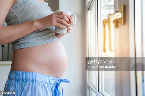 close-up of pregnant woman holding cup at the window - pregnant coffee 個照片及圖片檔