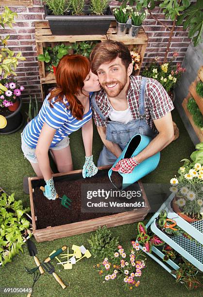couple preparing soil to plant vegetables in the container of their urban garden - terraced field stockfoto's en -beelden