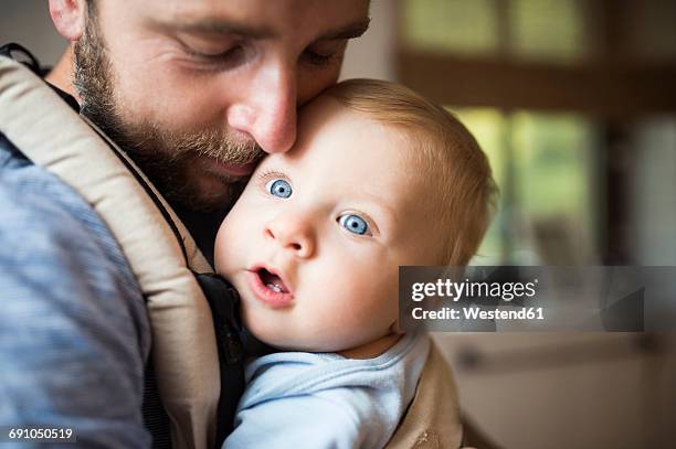 father cuddling with baby in baby carrier - baby beard stock-fotos und bilder