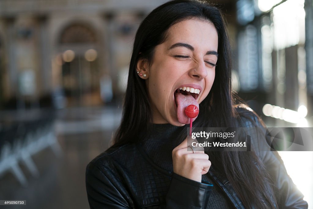 Portrait of young woman with lollipop pulling faces