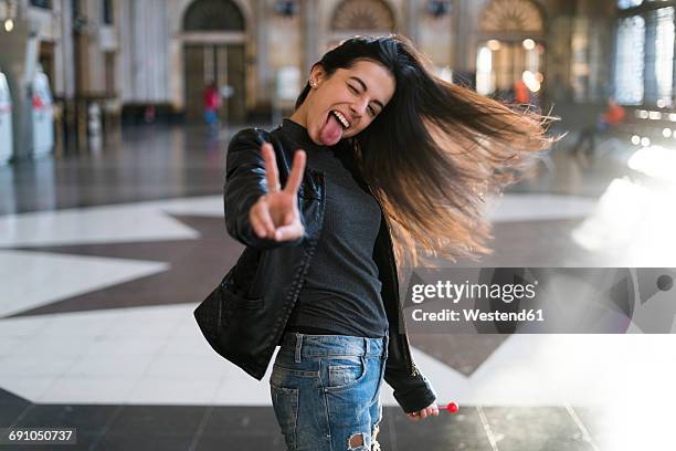 portrait of exuberant young woman with lollipop in station concourse - candy on tongue stock pictures, royalty-free photos & images