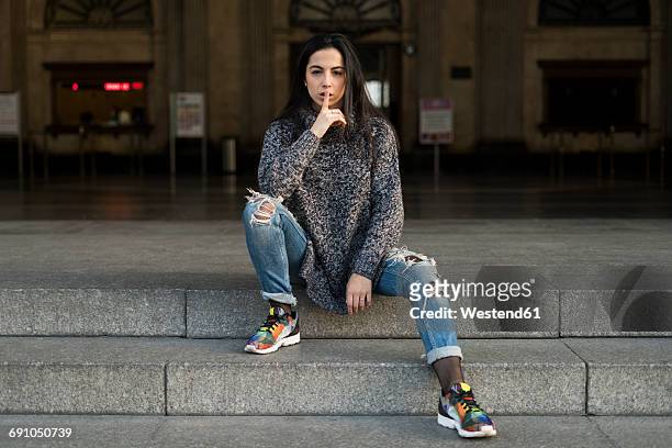 young woman sitting on stairs shushing - ripped jeans photos et images de collection
