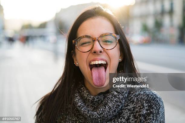 portrait of happy young woman with glasses sticking her tongue out - 舌を出す ストックフォトと画像