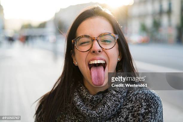 portrait of happy young woman with glasses sticking her tongue out - sticking out tongue stock pictures, royalty-free photos & images