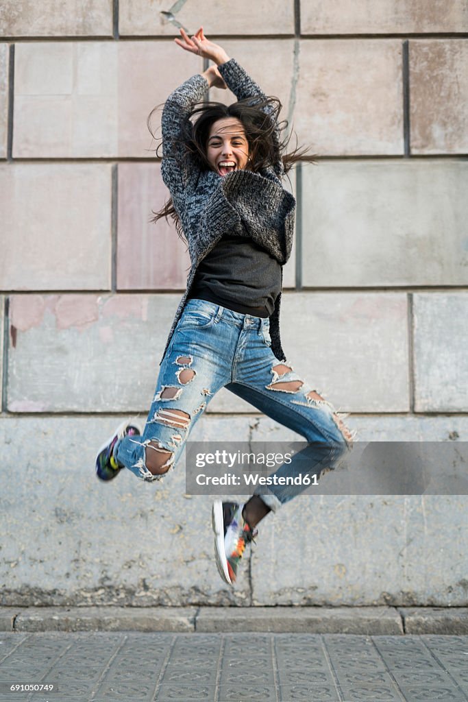 Portrait of exuberant young woman jumping around