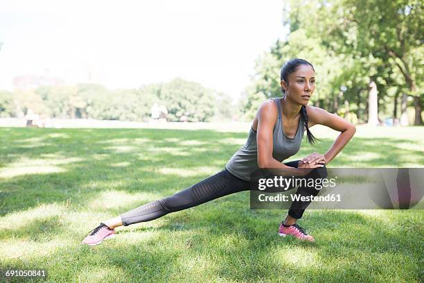 woman stretching on meadow in park - precalentamiento fotografías e imágenes de stock
