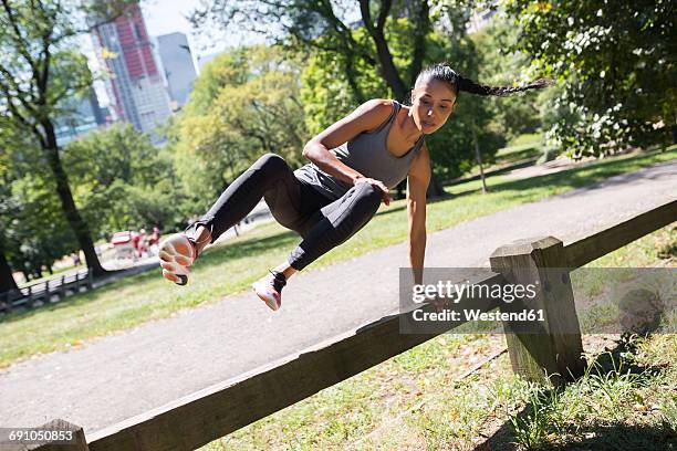 woman jumping over fence in park - conquering adversity stock pictures, royalty-free photos & images