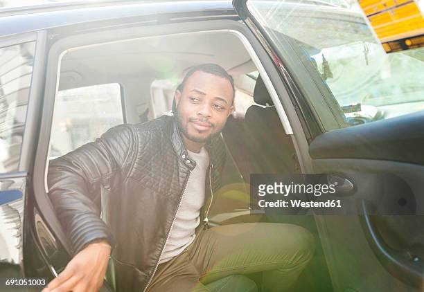 young man getting out of taxi - taxi españa stockfoto's en -beelden