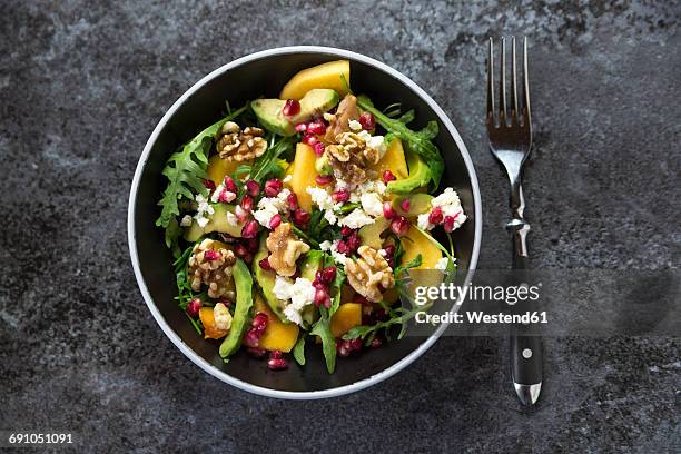 bowl of avocado salad with rocket, pomegranate seed, kaki, feta and walnuts - avocado salad stock pictures, royalty-free photos & images