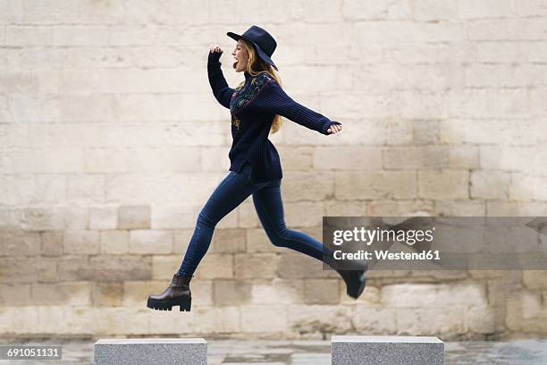 young woman jumping from bollard to bollard - dar brincos fotografías e imágenes de stock