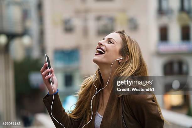 happy young woman listening music with earphones and smartphone - stadt begeisterung stock-fotos und bilder