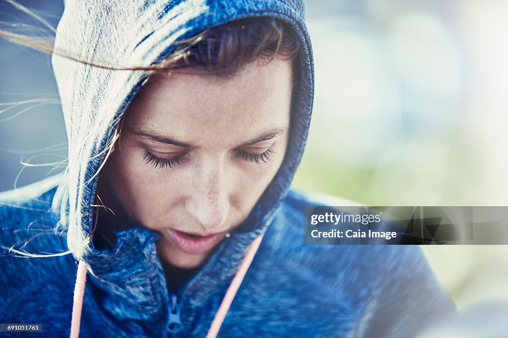 Close up female runner in hoody looking down