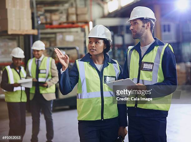 workers with clipboard talking in distribution warehouse - leanintogether stock pictures, royalty-free photos & images