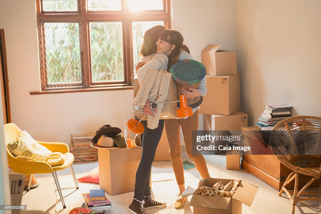 Mother and daughter hugging unpacking boxes in apartment